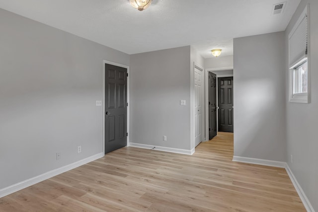 empty room with a textured ceiling and light wood-type flooring