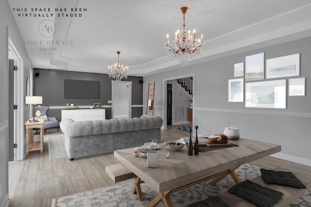 living room featuring a raised ceiling, light wood-type flooring, and a chandelier