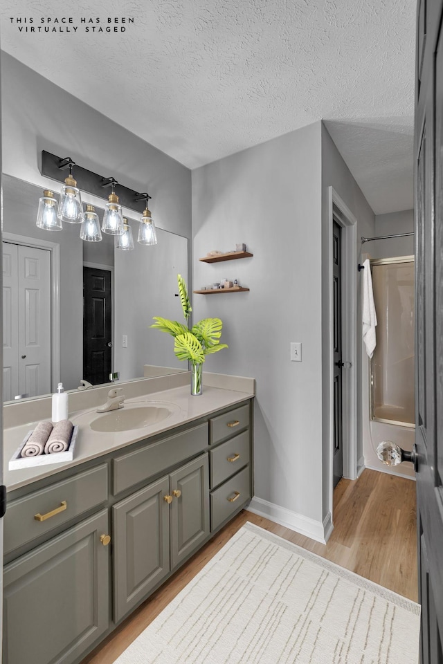 bathroom featuring wood-type flooring, vanity, a textured ceiling, and walk in shower