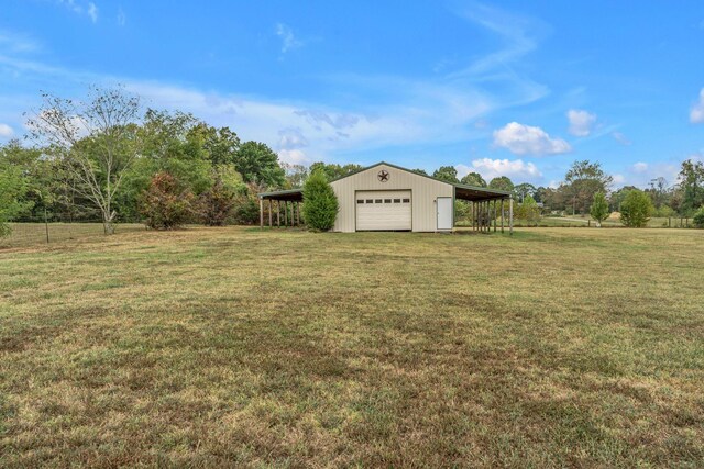 view of yard featuring a carport, an outdoor structure, and a garage