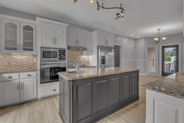 kitchen featuring a chandelier, appliances with stainless steel finishes, white cabinetry, and a kitchen island with sink