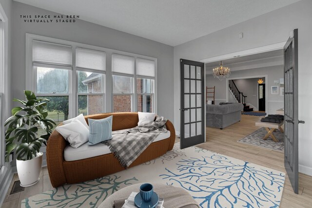 living room with a textured ceiling, light hardwood / wood-style flooring, a chandelier, and french doors