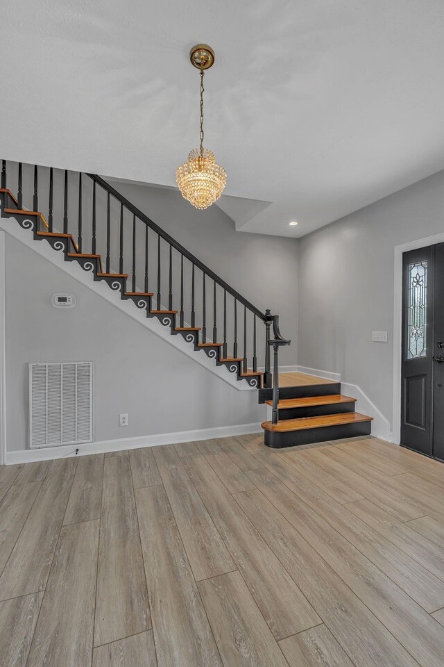 foyer entrance featuring light hardwood / wood-style floors and an inviting chandelier