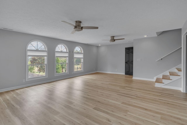 unfurnished living room with a textured ceiling, light hardwood / wood-style flooring, and ceiling fan