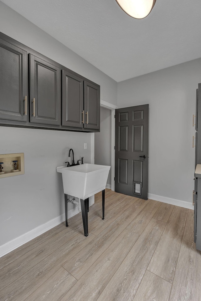 laundry room with cabinets, light wood-type flooring, and hookup for a washing machine