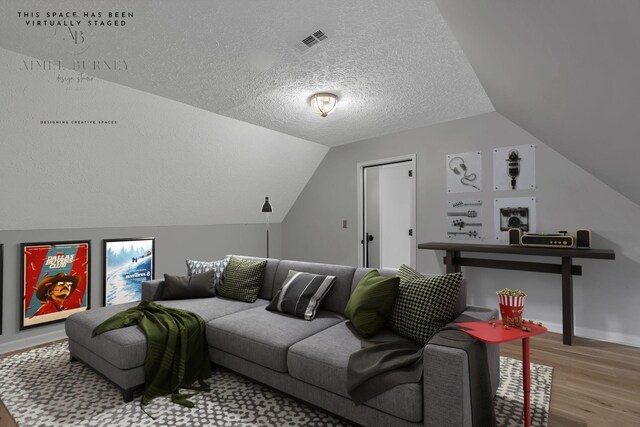 living room featuring vaulted ceiling, a textured ceiling, and light wood-type flooring