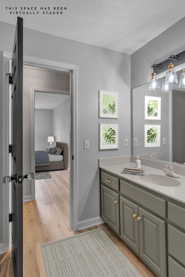 bathroom with hardwood / wood-style floors, vanity, and a textured ceiling