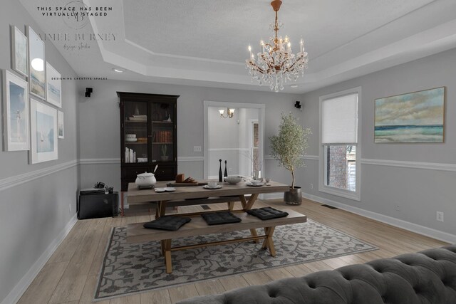 interior space featuring a chandelier, light wood-type flooring, and a tray ceiling