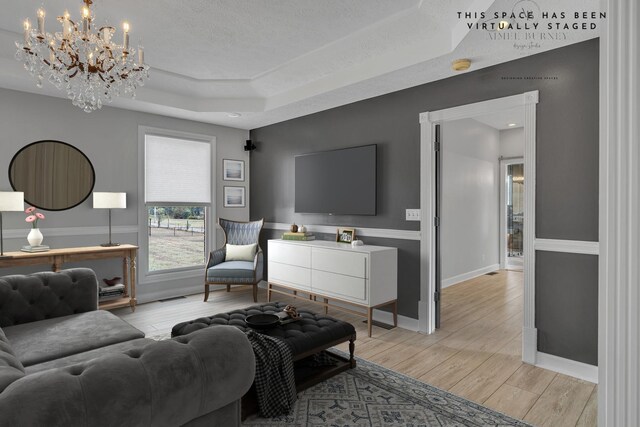 living room featuring a textured ceiling, a tray ceiling, and an inviting chandelier