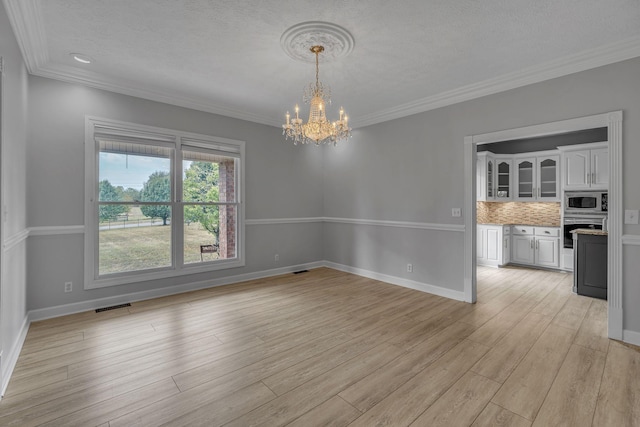 unfurnished dining area with ornamental molding, a textured ceiling, light hardwood / wood-style flooring, and a notable chandelier