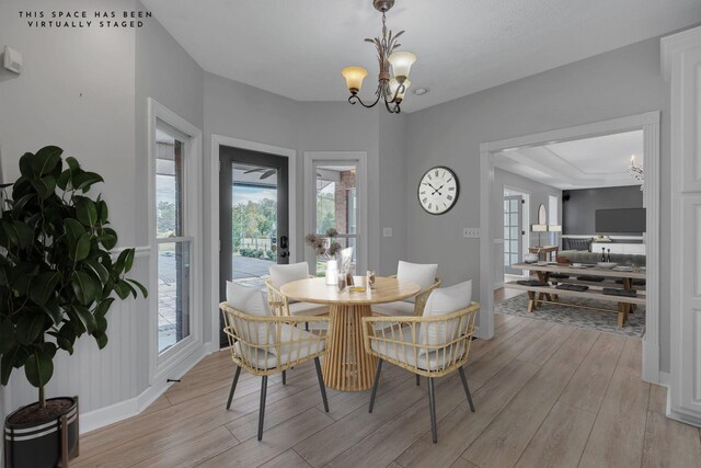 dining area with a notable chandelier, french doors, and light hardwood / wood-style flooring