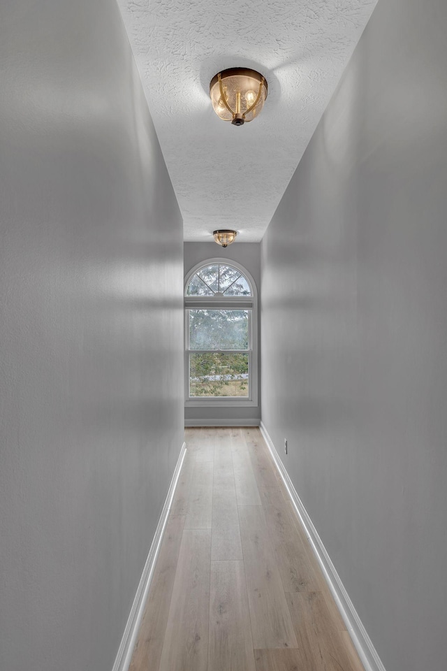 corridor featuring a textured ceiling and light wood-type flooring