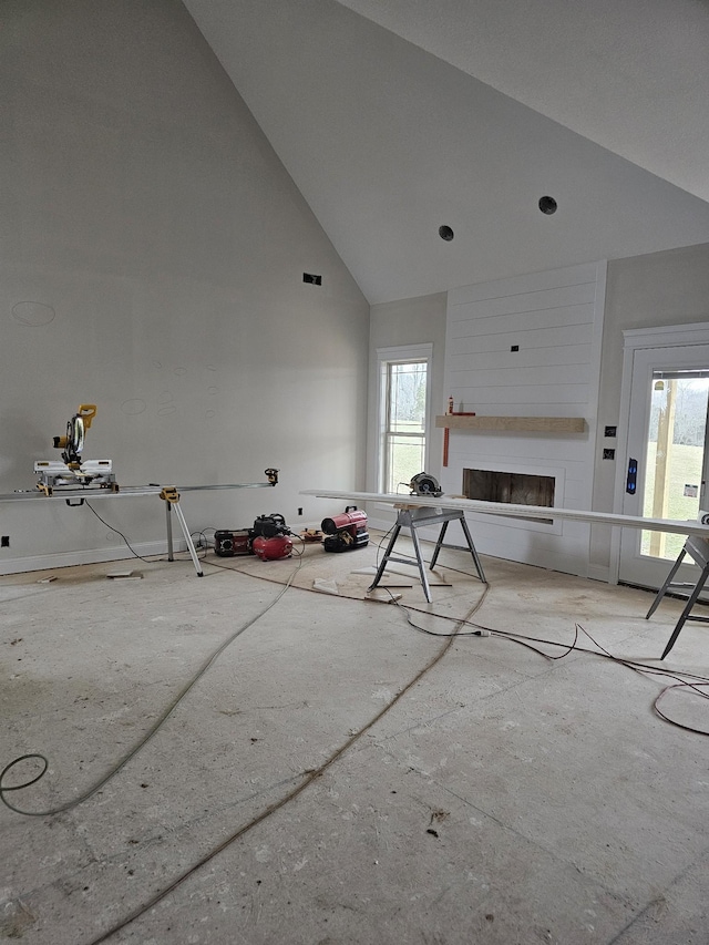 unfurnished living room featuring high vaulted ceiling, plenty of natural light, and a large fireplace