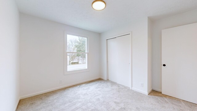 unfurnished bedroom featuring light colored carpet and a closet