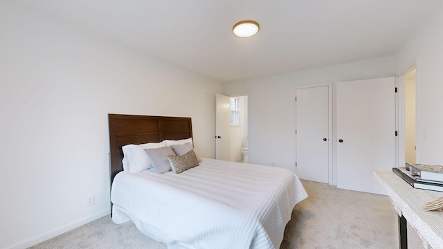 bedroom featuring light colored carpet and ensuite bath