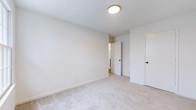 unfurnished bedroom with a closet, light carpet, and multiple windows