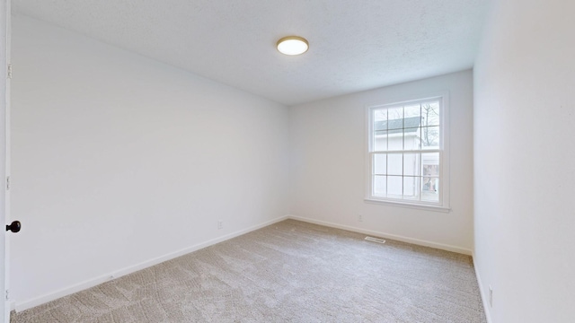 empty room with light carpet and a textured ceiling