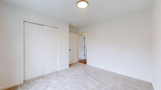 unfurnished bedroom with a closet and light colored carpet