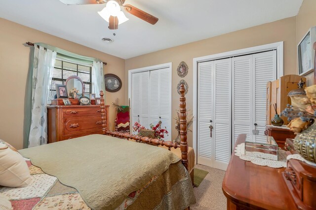 bedroom with light carpet, two closets, and ceiling fan