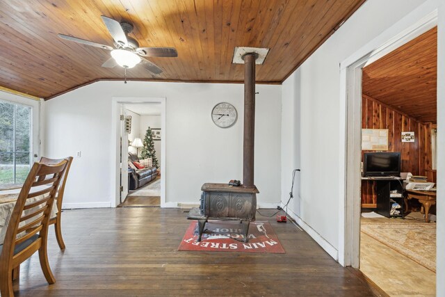 dining room with a wood stove, vaulted ceiling, ceiling fan, dark hardwood / wood-style flooring, and wood ceiling