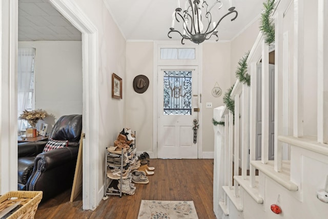 entryway with an inviting chandelier, crown molding, and dark wood-type flooring