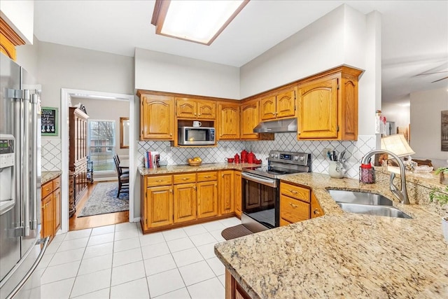 kitchen featuring appliances with stainless steel finishes, backsplash, light stone counters, sink, and light tile patterned floors