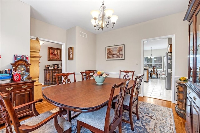 dining space featuring light wood-type flooring and an inviting chandelier