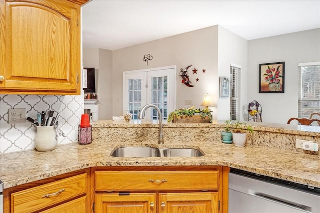 kitchen with dishwasher, backsplash, sink, light stone counters, and kitchen peninsula