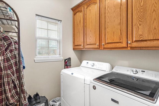 laundry area featuring washing machine and clothes dryer, a wealth of natural light, and cabinets