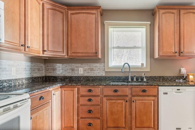 kitchen featuring dark stone countertops, white appliances, and sink