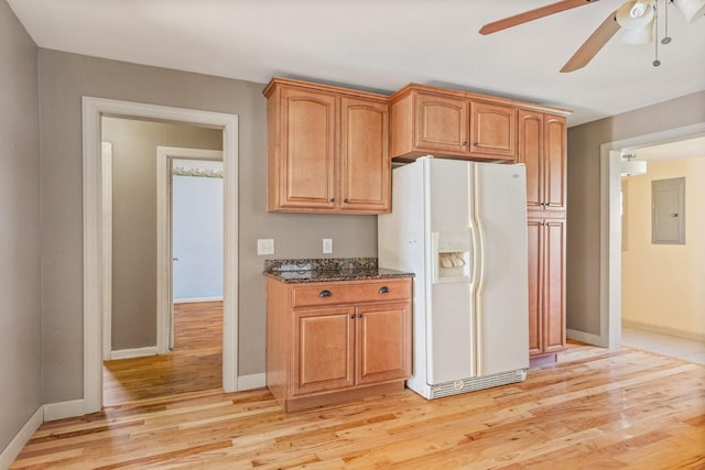 kitchen with white refrigerator with ice dispenser, light hardwood / wood-style floors, ceiling fan, and dark stone countertops