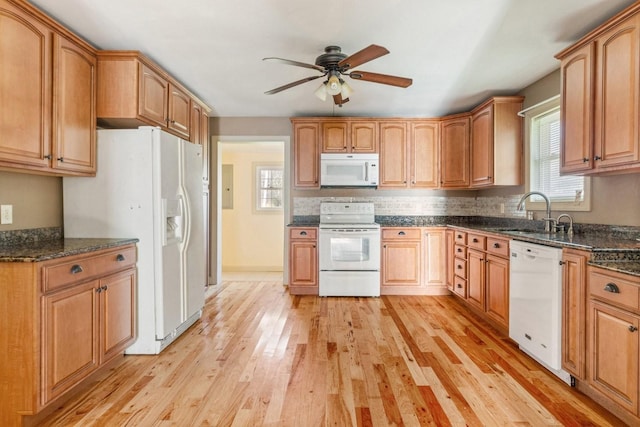 kitchen with white appliances, ceiling fan, sink, light hardwood / wood-style flooring, and dark stone countertops