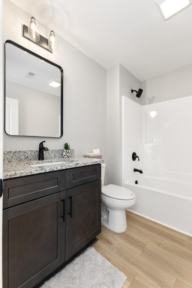 full bathroom with vanity, hardwood / wood-style flooring, toilet, and shower / washtub combination