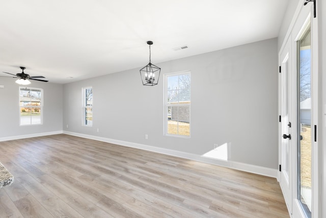 unfurnished dining area with ceiling fan with notable chandelier and light hardwood / wood-style floors