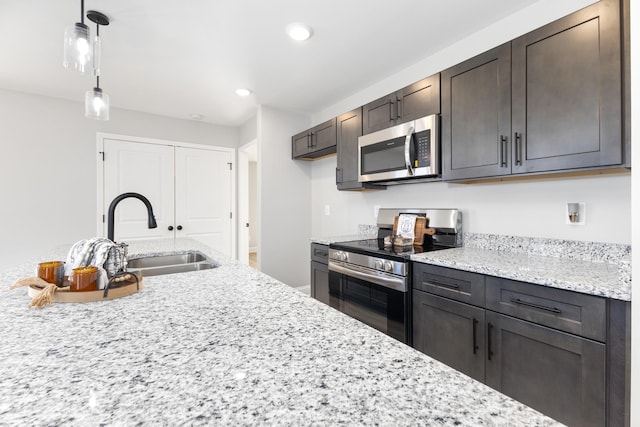 kitchen with light stone counters, sink, dark brown cabinets, and stainless steel appliances