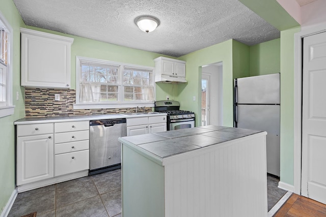 kitchen with sink, white cabinetry, tile countertops, stainless steel appliances, and backsplash