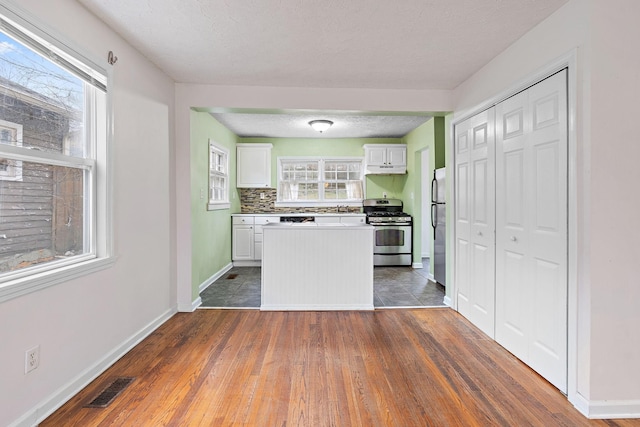 kitchen featuring stainless steel appliances, white cabinetry, a healthy amount of sunlight, and backsplash