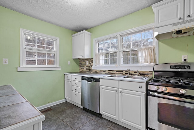 kitchen with sink, white cabinetry, stainless steel appliances, a healthy amount of sunlight, and decorative backsplash