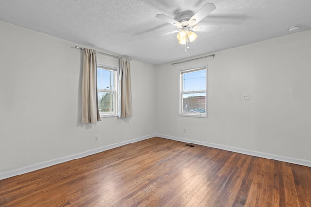 unfurnished room with ceiling fan, plenty of natural light, dark wood-type flooring, and a textured ceiling