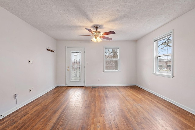 empty room with hardwood / wood-style flooring, a healthy amount of sunlight, a textured ceiling, and ceiling fan