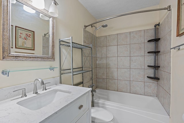 full bathroom featuring tiled shower / bath, vanity, toilet, and a textured ceiling