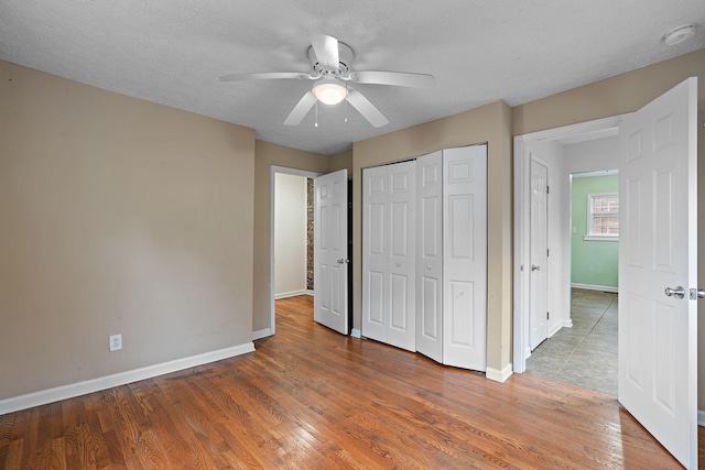 unfurnished bedroom featuring ceiling fan, hardwood / wood-style floors, a textured ceiling, and a closet