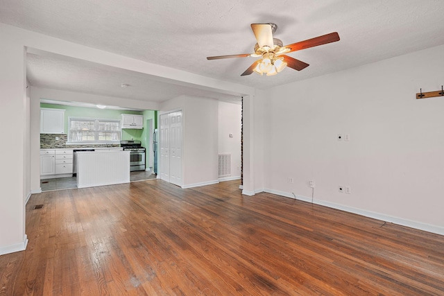 unfurnished living room featuring ceiling fan, dark hardwood / wood-style floors, and a textured ceiling