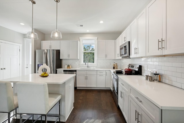 kitchen with white cabinets, hanging light fixtures, appliances with stainless steel finishes, and tasteful backsplash