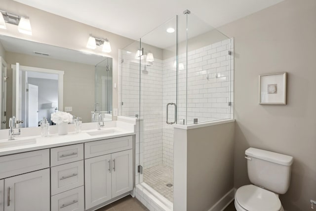 bathroom featuring tile patterned flooring, a shower with door, vanity, and toilet