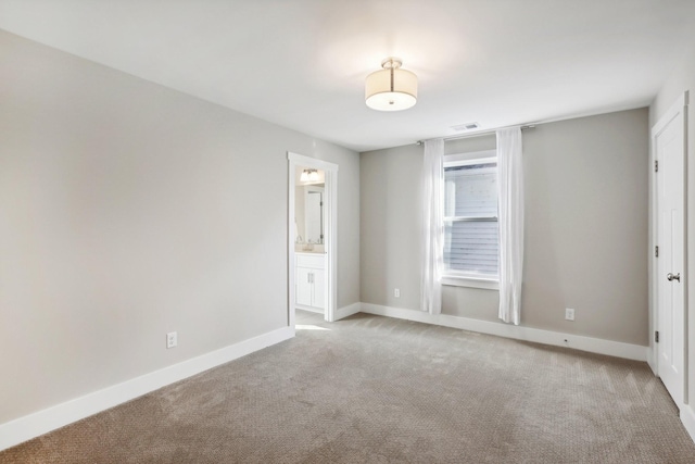 unfurnished bedroom featuring light colored carpet and ensuite bath