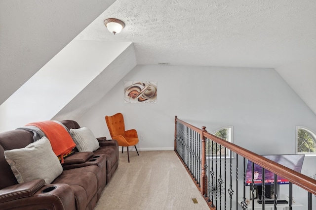 interior space featuring a textured ceiling, light colored carpet, and lofted ceiling