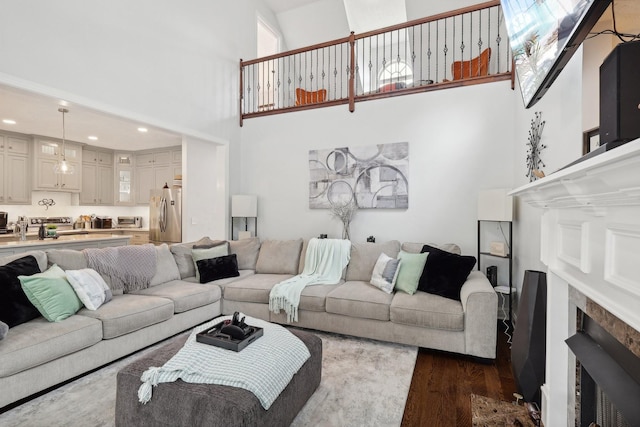 living room with a fireplace, a high ceiling, and dark wood-type flooring