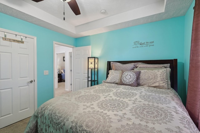 carpeted bedroom with a tray ceiling and ceiling fan