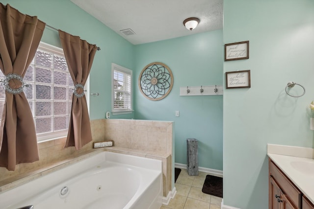 bathroom with tile patterned floors, a bathtub, a textured ceiling, and vanity